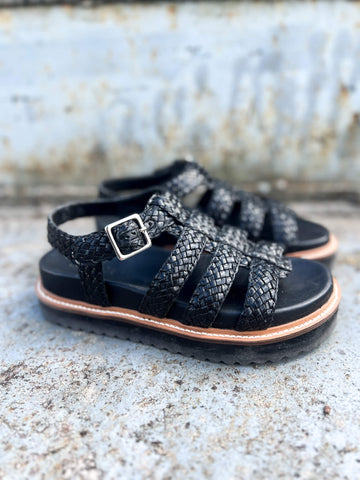 Step up your summer style with the 6GL0091002 2100 black gladiator-style slipper. Designed with sleek woven straps and a trendy flatform sole, this sandal is finished with an adjustable buckle closure for a secure and stylish fit. Perfect for casual days or evenings out, this bold design effortlessly elevates any outfit.